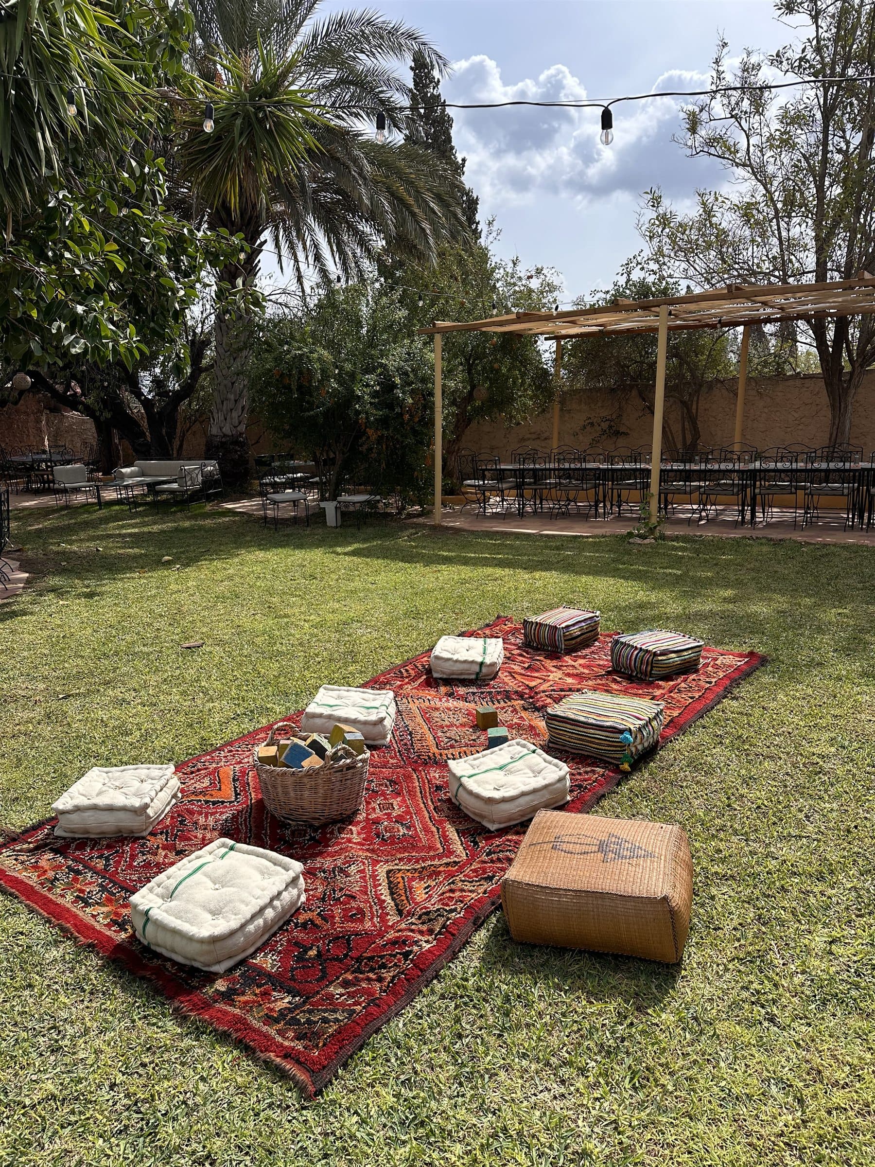 Salon de jardin bohème, coussins et tapis kilim sous les palmiers